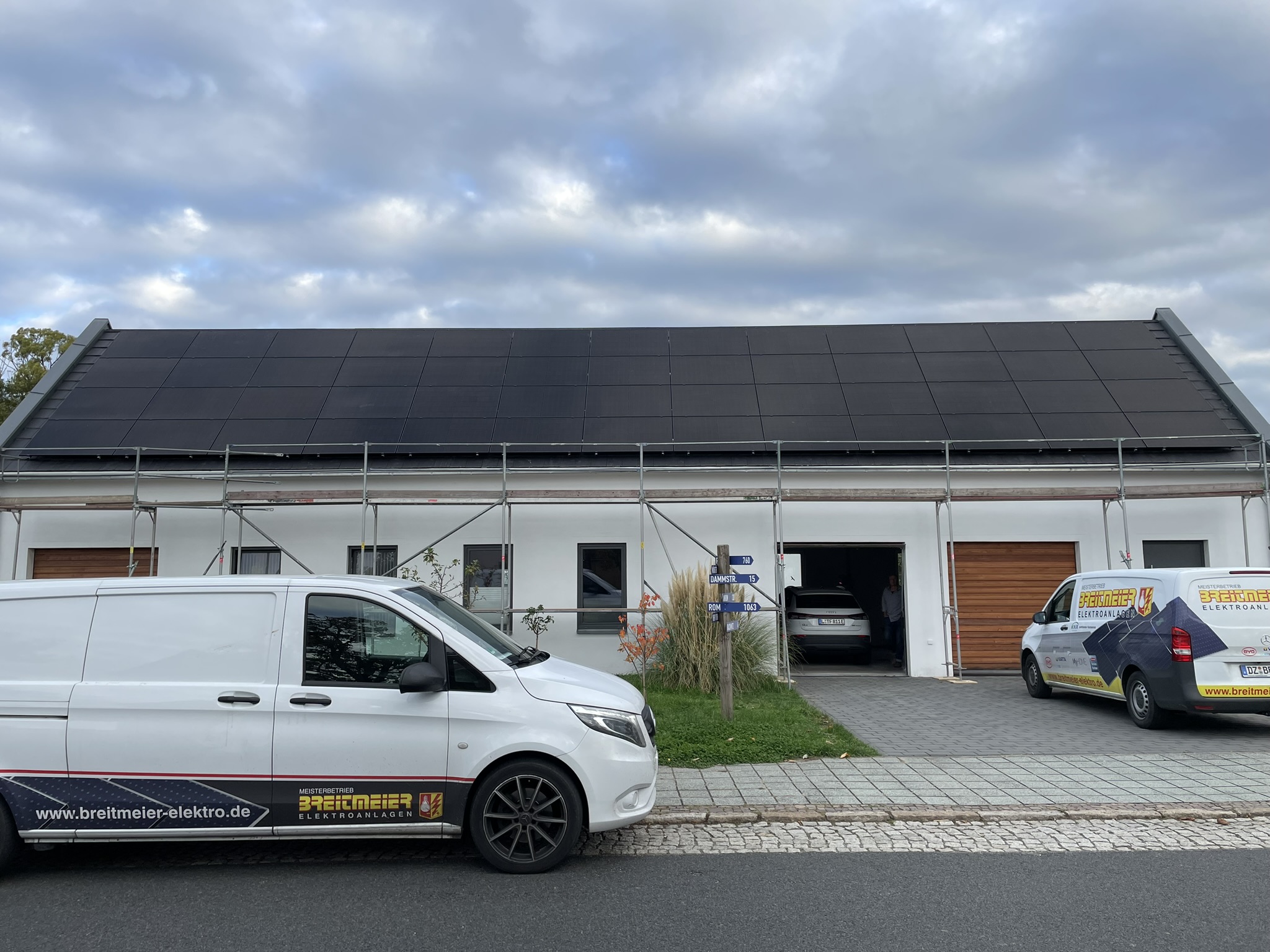 Team und Firmenwagen vor fertiger PV-Anlage